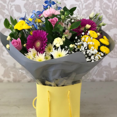 Bright Blooms Bouquet - A cheerful bouquet featuring a mix of vibrant colors, including pinks, yellows, and blues, arranged in a stylish yellow gift bag.