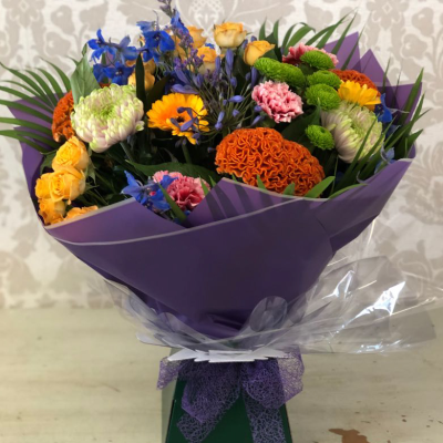 Vibrant Celebration Bouquet - A bold and lively bouquet with a mix of bright oranges, blues, and yellows, elegantly wrapped in paper, perfect for any celebration.